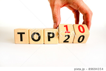 From Top 20 to 10 symbol. Businessman turns wooden cubes and changes concept words Top 20 to Top 10. Beautiful white table white background. Business and from Top 20 to Top 10 concept. Copy space. 89694354