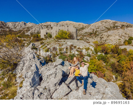 Happy family on the background of Collapsing tower of fortress Kosmac. Travel to Montenegro concept. Ancient Austro-Hungarian fortress built as a defensive structure and an observation post. Montenego Happy family on the background of Collapsing tower of fortress Kosmac. Travel to Montenegro concept. Ancient Austro-Hungarian fortress built as a defensive structure and an observation post. Montenego 89695163