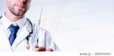 Syringe needle medical injection. Selective focus, doctor hand in blue gloves holding syringe with needle. Hospital white doctor gown, stethoscope. Syringe with flu vaccine with copy space. 89695697