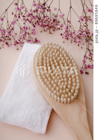 Wooden massage brush with natural bristles and towel for spa. Healthy and firm skin concept. Vertical image Wooden massage brush with natural bristles and towel for spa. Healthy and firm skin concept. Vertical image 89695849