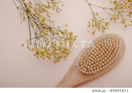 Dry wooden brush near yellow branch of gypsophila close-up. Spa and self care concept Dry wooden brush near yellow branch of gypsophila close-up. Spa and self care concept 89695851