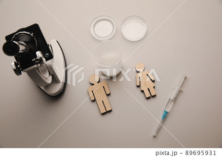 A syringe, wooden couple and microscope at laboratory. Pregnancy, healt care and analysis concept 89695931