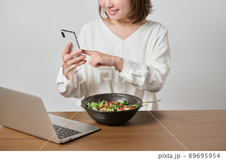 スマホを見ながらオートミールを食べる若いヴィーガン女性 89695954