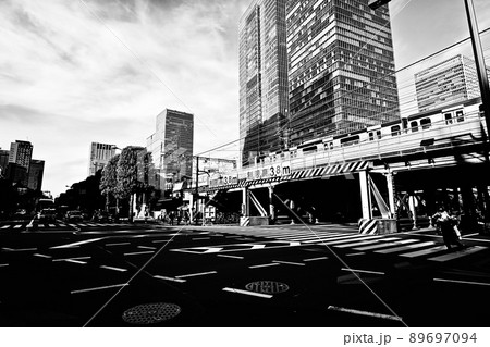 モノクローム　鉄道風景　高架橋と交差点と高層ビル　青空に浮ぶ筋状の雲　東京駅周辺の光景 89697094