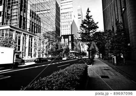 モノクローム東京大手町の光景　高層ビルの谷間を走る車　歩道と街路樹　オフィス街の光景 89697096
