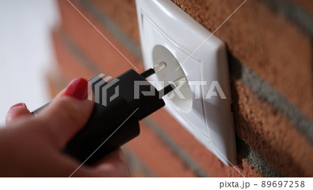 Closeup of woman holding hand and inserting plug into socket 89697258