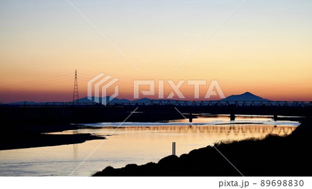 昭和橋から撮影した冬の早朝の遠くに筑波山の山並みと東武伊勢崎線の橋梁が見える利根川の風景 89698830