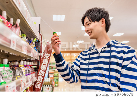 スーパーで栄養ドリンクを買う若い男性 89706079