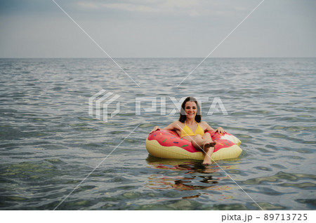 slender girl swims on an inflatable circle in the sea in summer 89713725
