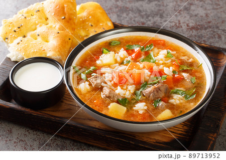 Tomato spicy soup with lamb, rice and vegetables close-up in a bowl served with flat bread. horizontal 89713952