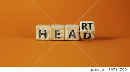 Heart or head symbol. Turned a wooden cube and changed the word head to heart. Beautiful orange table, orange background, copy space. Medical, lyfestyle and heart or head concept. Heart or head symbol. Turned a wooden cube and changed the word head to heart. Beautiful orange table, orange background, copy space. Medical, lyfestyle and heart or head concept. 89714709