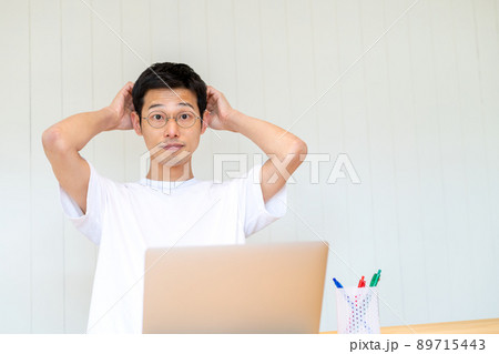 パソコン作業に行き詰まって頭を抱えつつ目が点になっている男性 パソコン作業に行き詰まって頭を抱えつつ目が点になっている男性 89715443