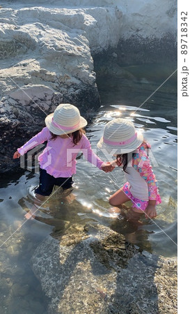 海で遊ぶ麦わら帽子の双子の女の子 89718342