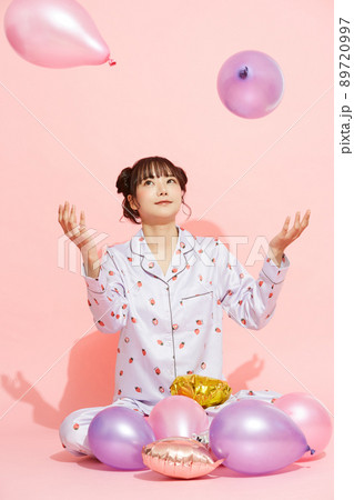 パジャマを着た若い女性のピンク背景のポートレート 89720997