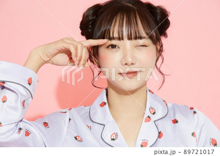 パジャマを着た若い女性のピンク背景のポートレート 89721017