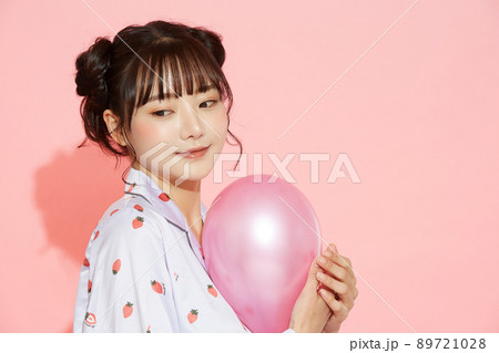 パジャマを着た若い女性のピンク背景のポートレート 89721028