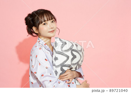 パジャマを着た若い女性のピンク背景のポートレート 89721040