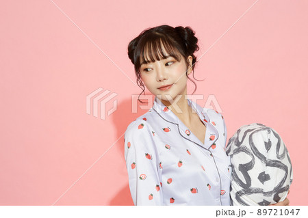 パジャマを着た若い女性のピンク背景のポートレート 89721047