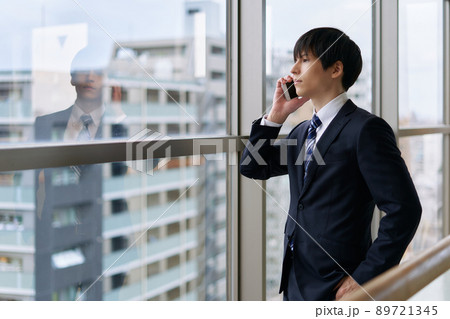 外を眺めながら電話で話すビジネスマン 89721345