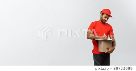 Delivery Concept - Portrait of Handsome African American delivery man or courier writing on a order document. Isolated on Grey studio Background. Copy Space. 89723699