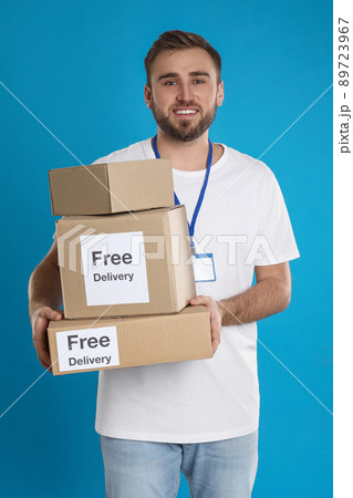 Male courier holding parcels with stickers Free Delivery on light blue background Male courier holding parcels with stickers Free Delivery on light blue background 89723967