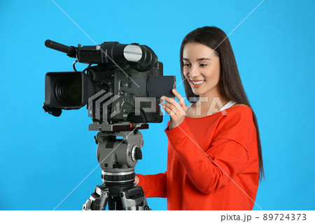 Operator with professional video camera on blue background 89724373