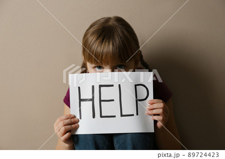 Abused little girl showing with phrase HELP ME near blue wall, focus on hand. Abused little girl showing with phrase HELP ME near blue wall, focus on hand. 89724423