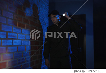 Male security guard with flashlight in dark corridor 89724666