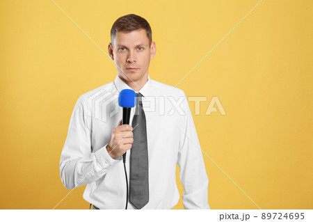 Male journalist with microphone on yellow background 89724695