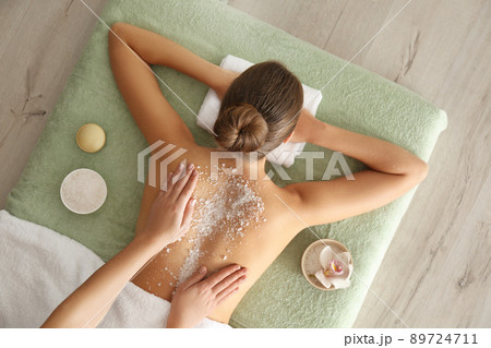 Young woman having body scrubbing procedure with sea salt in spa salon, top view 89724711