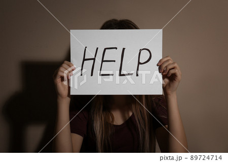 Abused young woman showing palm with word STOP near beige wall, focus on hand 89724714