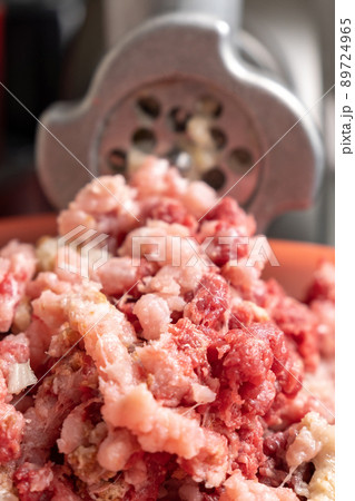 Meat grinder and mince comes out of it. Minced meat, meat delicacies, fresh home food. Homemade food. Vertical photo 89724965