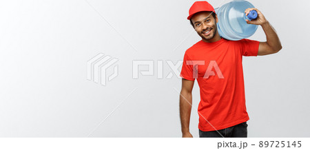 Delivery Concept - Handsome African American delivery man holding water tank. Isolated on Grey studio Background. Copy Space. 89725145