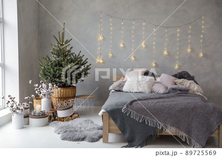 Little Christmas tree with fairy lights in bedroom interior Little Christmas tree with fairy lights in bedroom interior 89725569