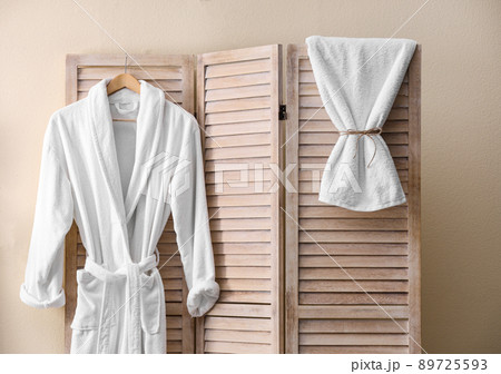 Soft comfortable bathrobe hanging on folding screen in stylish room interior Soft comfortable bathrobe hanging on folding screen in stylish room interior 89725593