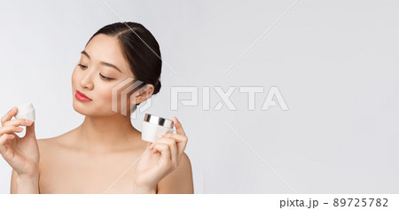 Beautiful young woman on white isolated background holding cosmetic face cream, asian Beautiful young woman on white isolated background holding cosmetic face cream, asian 89725782