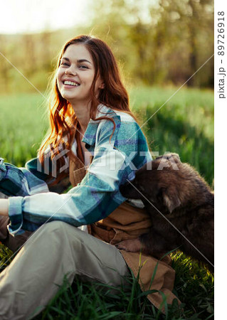 Woman on the grass with her dog in the park in the evening with sunshine smiling 89726918