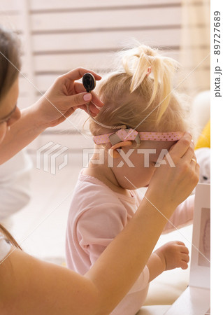 Mother helps her baby put on part of cochlear implant - Deaf child with hearing aid at home Mother helps her baby put on part of cochlear implant - Deaf child with hearing aid at home 89727689