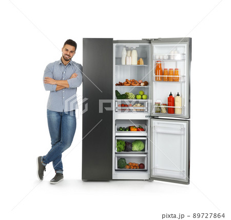 Young man near open refrigerator on white background 89727864