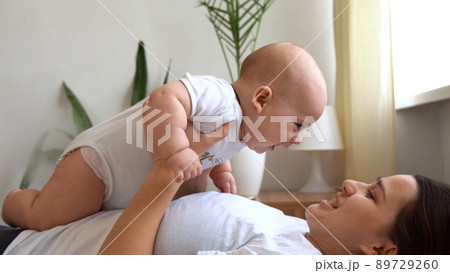 Authentic Young Caucasian Woman Holding Newborn Baby. Mom And Child On Bed. Close-up Portrait of Smiling Family With Infant On Hands. Happy Marriage Couple On Background. Childhood, Parenthood Concept Authentic Young Caucasian Woman Holding Newborn Baby. Mom And Child On Bed. Close-up Portrait of Smiling Family With Infant On Hands. Happy Marriage Couple On Background. Childhood, Parenthood Concept 89729260