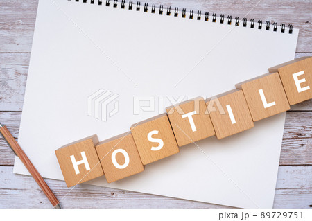 敵意・敵のイメージ｜「HOSTILE」と書かれた積み木、ノート、ペン、手 89729751