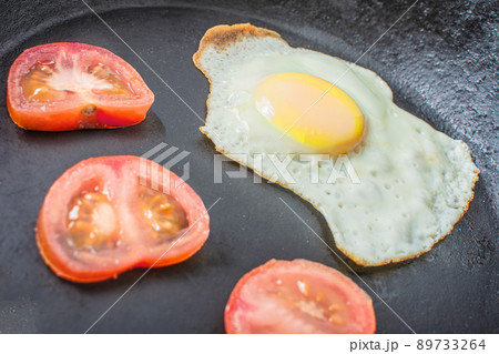 Egg, sunny side up, with fresh tomatoes in a frying pan Egg, sunny side up, with fresh tomatoes in a frying pan 89733264