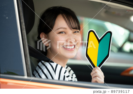 運転席で初心者マークを持つ笑顔の若い女性 運転席で初心者マークを持つ笑顔の若い女性 89739117