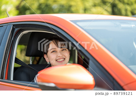 運転する車の窓から顔を出す笑顔の若い女性 89739121