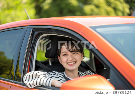 運転する車の窓から顔を出す笑顔の若い女性 運転する車の窓から顔を出す笑顔の若い女性 89739124