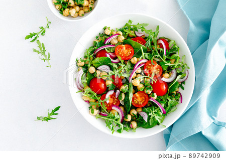 Vegetarian chickpea salad with tomatoes, arugula, parsley, spinach and red onion. Healthy food, diet. Top view Vegetarian chickpea salad with tomatoes, arugula, parsley, spinach and red onion. Healthy food, diet. Top view 89742909
