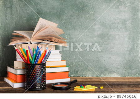 Stack of books and stationery on the background of the school board. 89745016