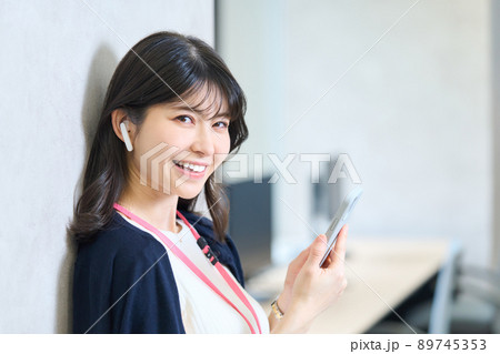 壁にもたれスマホを持つ女性 89745353