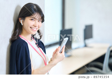 壁にもたれスマホを持つ女性 89745354