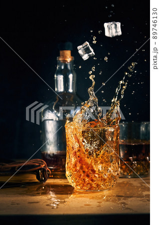 ice falls into a glass of cognac ice falls into a glass of cognac 89746130